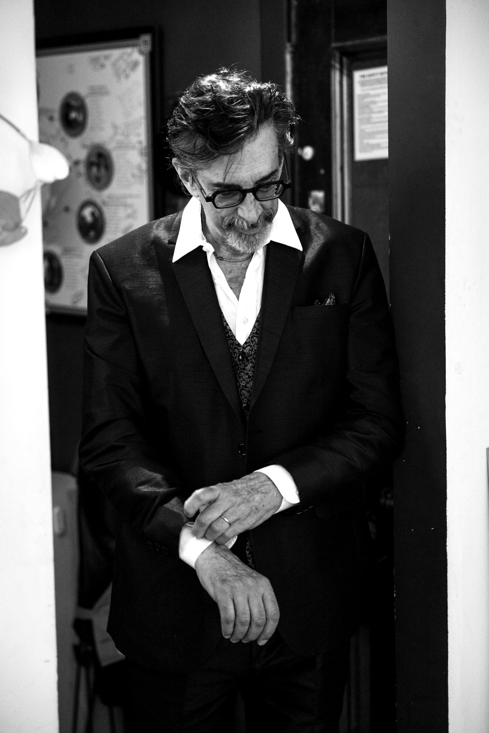 Ritt Henn in a dark suit, adjusting his cuff